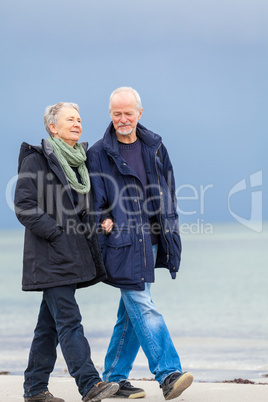 happy elderly senior couple walking on beach