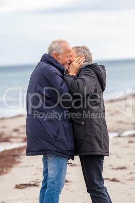 happy elderly senior couple walking on beach