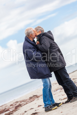 happy elderly senior couple walking on beach