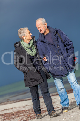 happy elderly senior couple walking on beach