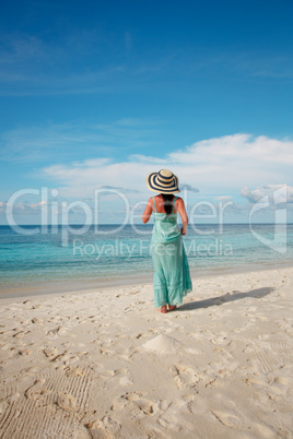 Girl walking along a tropical beach in the Maldives.