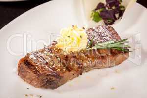 Grilled beef steak topped with butter and rosemary