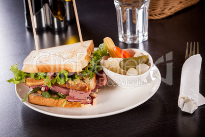 Delicious pastrami club sandwich and pickles