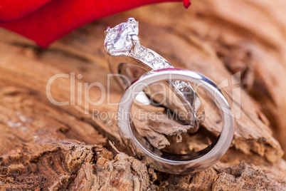 beautiful ring on wooden background and red rose