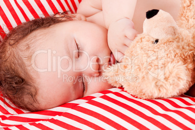 sleeping cute little baby on red and white stripes pillow