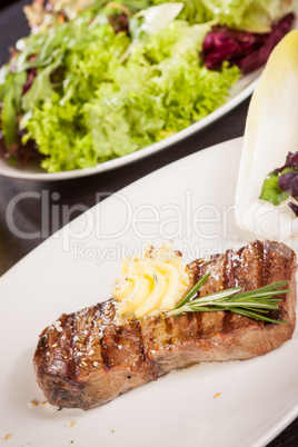 Grilled beef steak topped with butter and rosemary