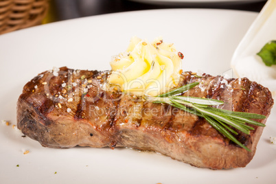 Grilled beef steak topped with butter and rosemary