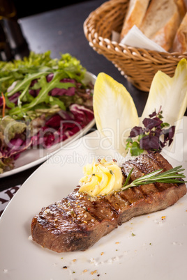 Grilled beef steak topped with butter and rosemary