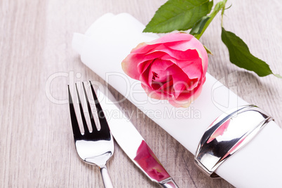 Table setting with a single pink rose