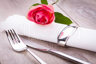 Table setting with a single pink rose