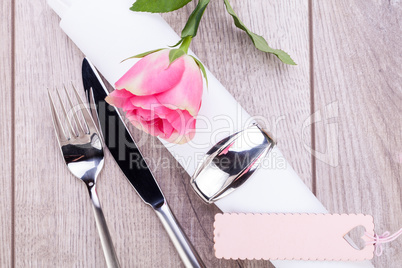 Table setting with a single pink rose