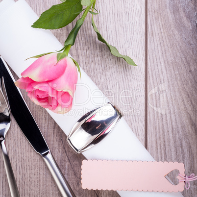 Table setting with a single pink rose