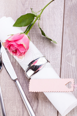 Table setting with a single pink rose