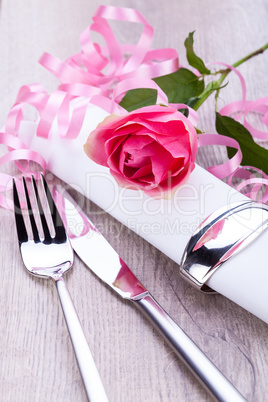 Table setting with a single pink rose