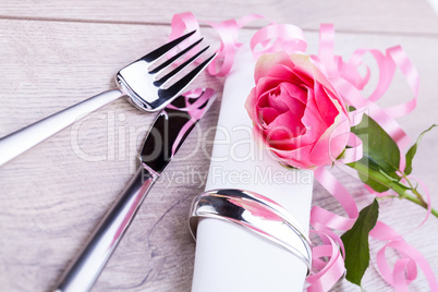 Table setting with a single pink rose