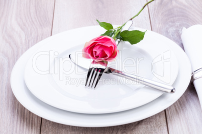 Table setting with a single pink rose