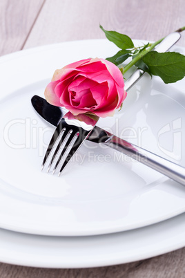 Table setting with a single pink rose