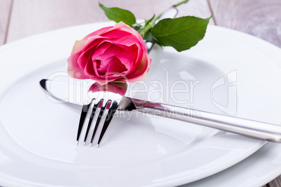 Table setting with a single pink rose