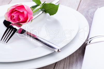 Table setting with a single pink rose