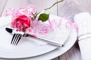 Table setting with a single pink rose