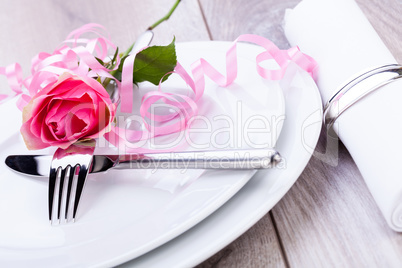 Table setting with a single pink rose