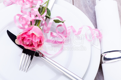 Table setting with a single pink rose