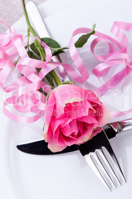 Table setting with a single pink rose