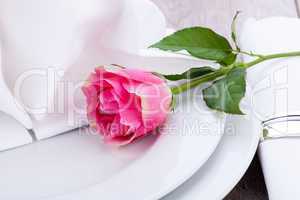 Table setting with a single pink rose