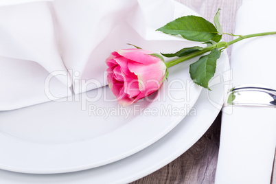 Table setting with a single pink rose