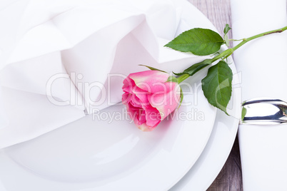 Table setting with a single pink rose