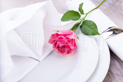 Table setting with a single pink rose