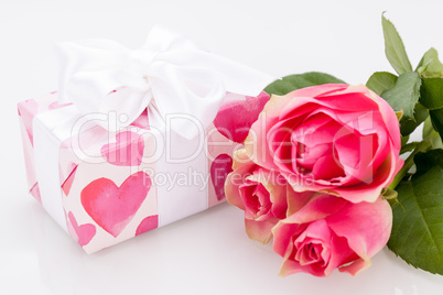 Gift box with an empty tag, next to three roses