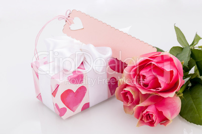 Gift box with an empty tag, next to three roses