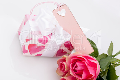 Gift box with an empty tag, next to three roses