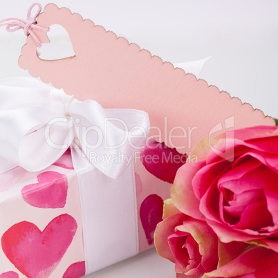 Gift box with an empty tag, next to three roses