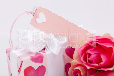 Gift box with an empty tag, next to three roses