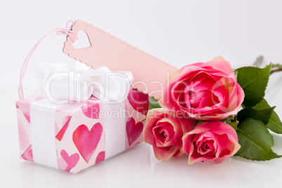 Gift box with an empty tag, next to three roses