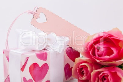 Gift box with an empty tag, next to three roses