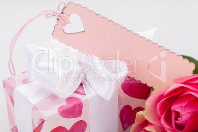 Gift box with an empty tag, next to three roses