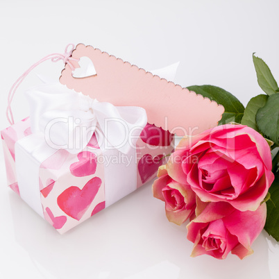 Gift box with an empty tag, next to three roses