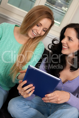 two young attractive girl with tablett pc on couch