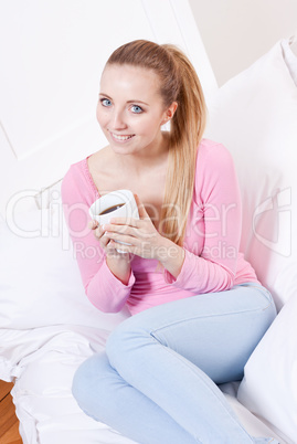 smiling young blonde woman drinking coffee