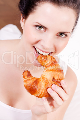 smiling woman eating a croissant