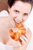 smiling woman eating a croissant