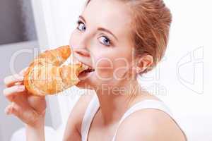 attractive young woman eating croissant