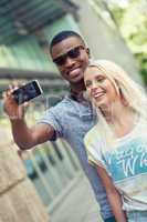 young smiling multiracial couple taking foto by smartphone