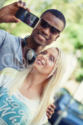 young smiling multiracial couple taking foto by smartphone