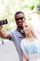 young smiling multiracial couple taking foto by smartphone