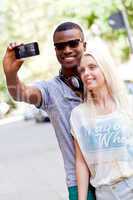 young smiling multiracial couple taking foto by smartphone