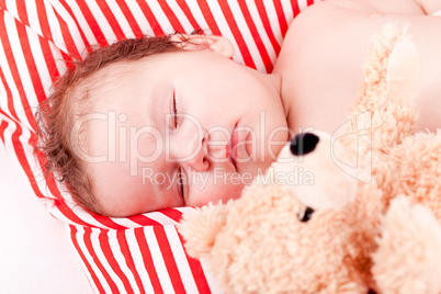 sleeping cute little baby on red and white stripes pillow